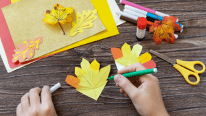 a person is cutting out paper leaves with scissors